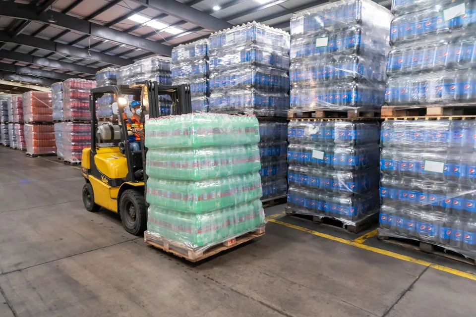 Forklift moving pallets of beverages in a distribution warehouse